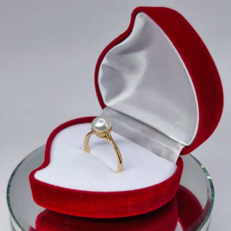 złoty pierścionek 585 z masą perłową położony w czerwonym opakowaniu z serca